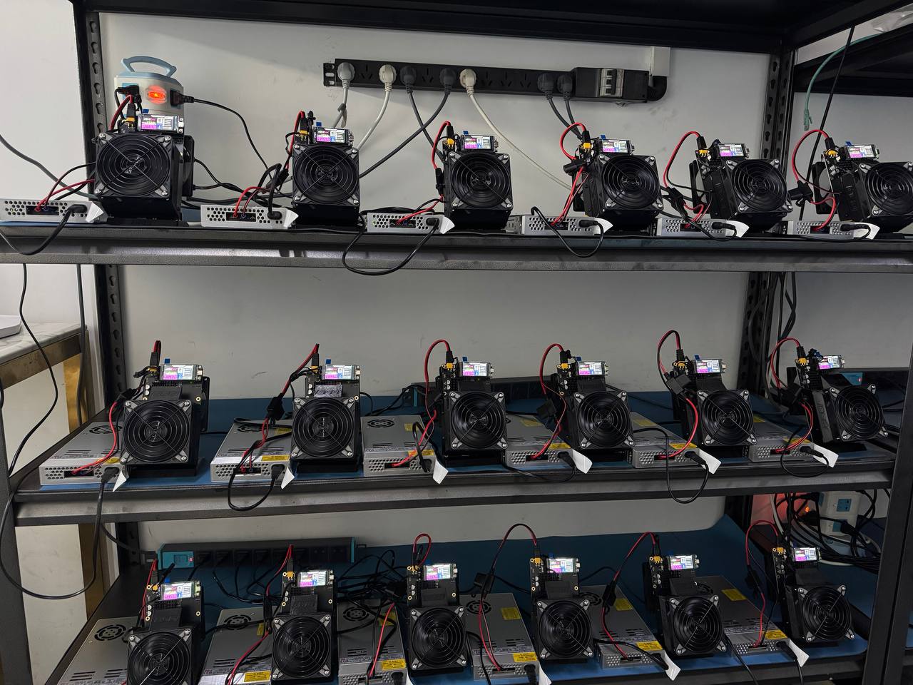 NerdQaxe++ rack — three shelves of units running on Meanwell LRS-series PSUs at Helium Deploy